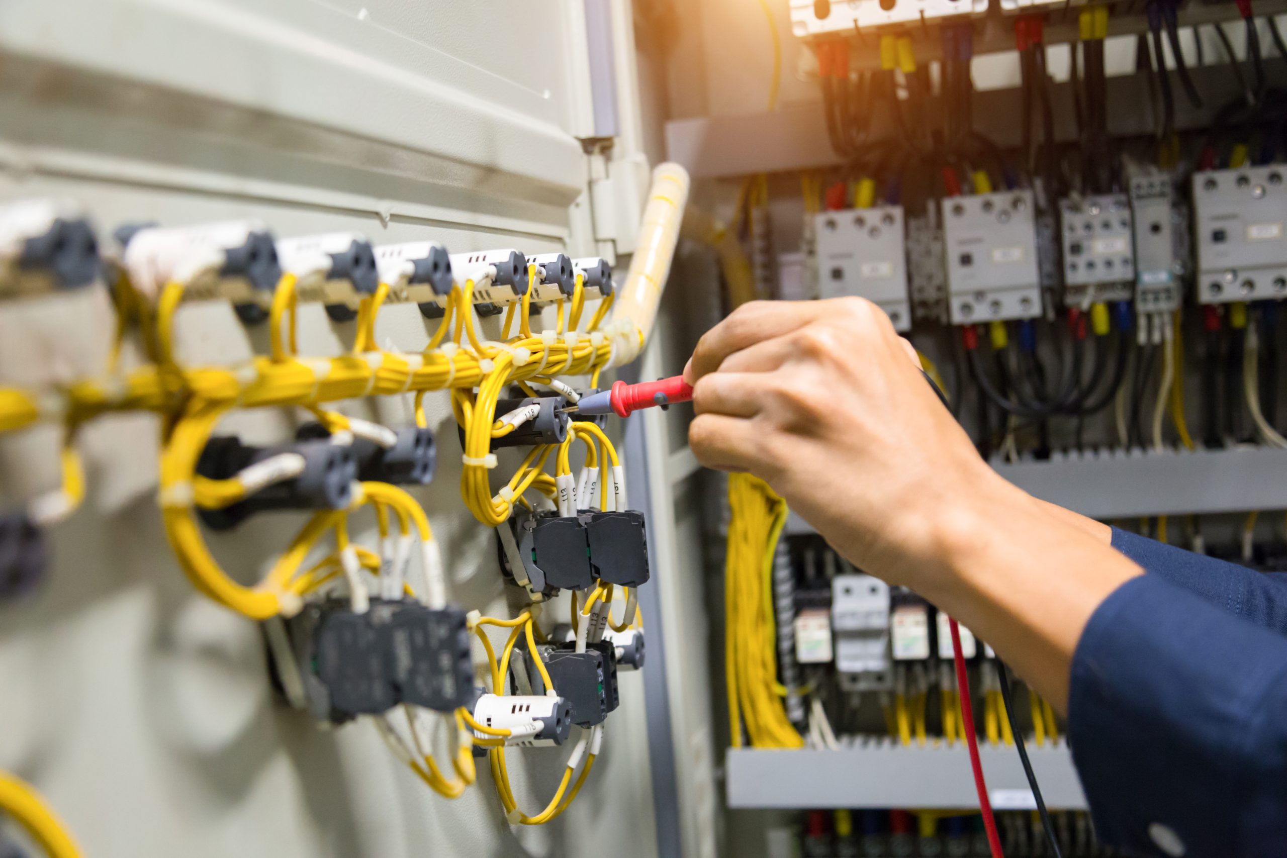 Electricians hands testing current  electric in control panel.