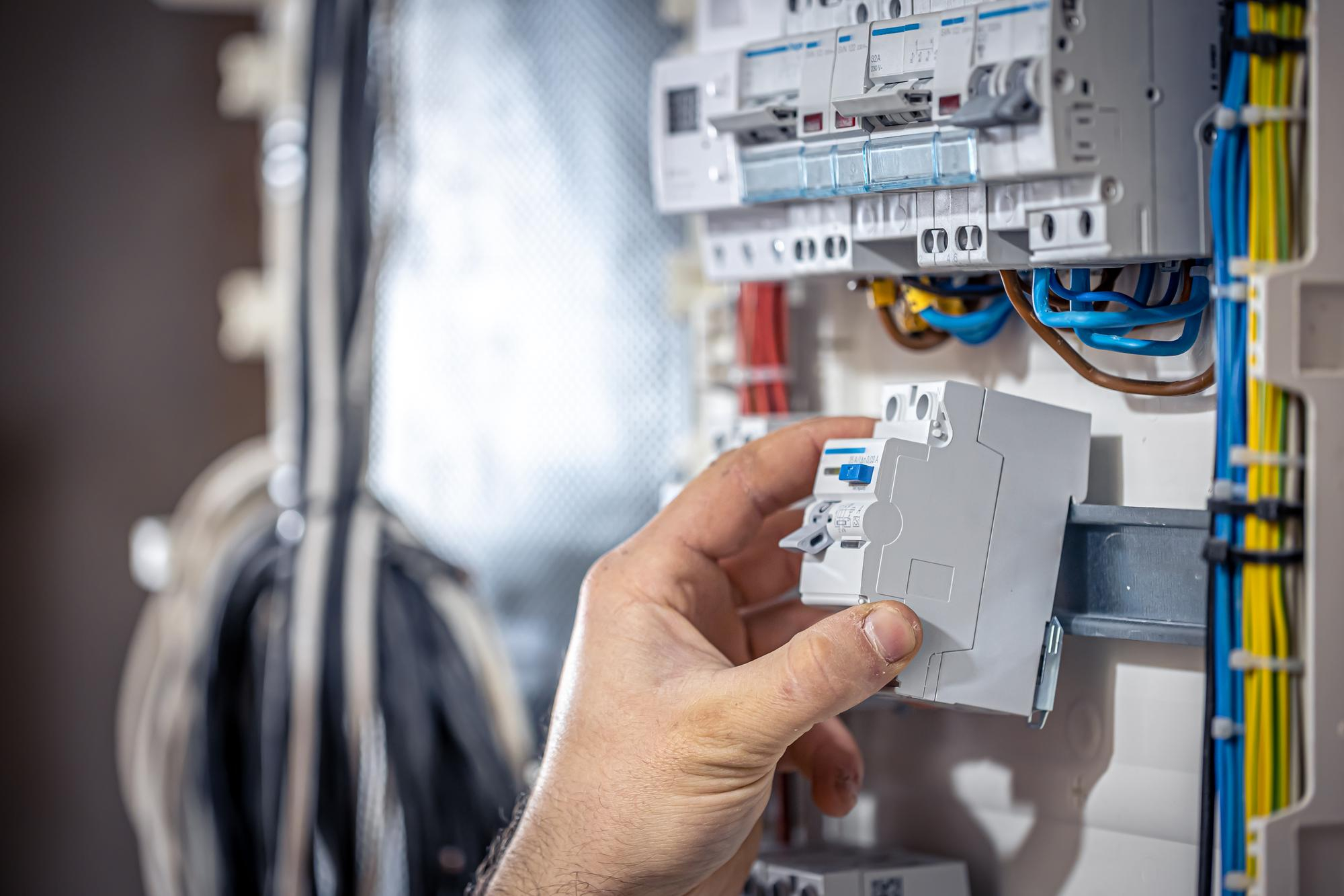 male-electrician-works-switchboard-with-electrical-connecting-cable