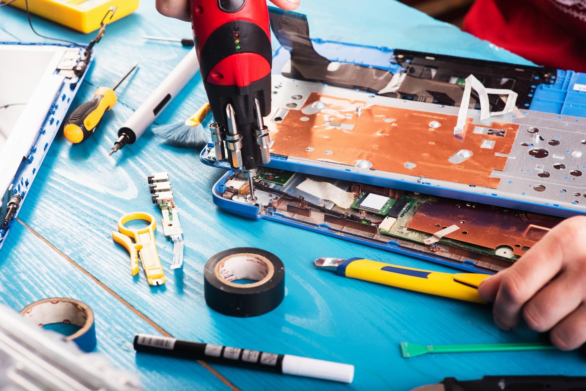 wizard-repairs-laptop-with-tools-hands-blue-wooding-table-top-view